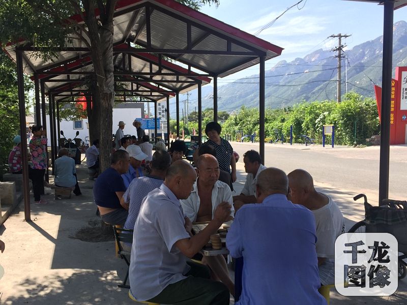 现在,刘大爷吃过午饭,就会去村口新修的休闲区跟老伙伴儿们玩牌、下棋,偶尔也会用路旁新安装的健身器材锻炼身体。图为午后村口休闲区内,村民们正在下棋。千龙网记者 薄晨棣摄