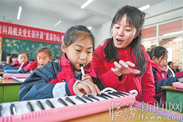 特色音乐课堂上,老师指导学生吹口风琴。.jpg