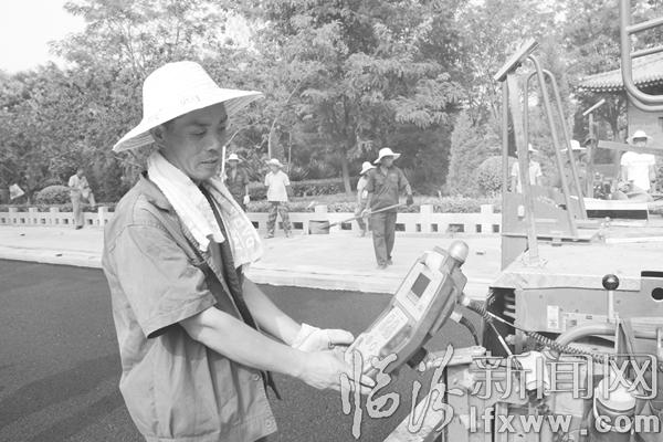 施工人员边观察铺油设备仪表,边进行道路铺油作业