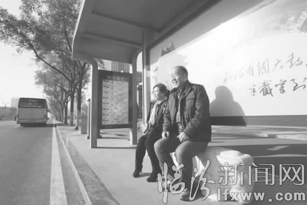 图为市民坐在石雕座椅上候车