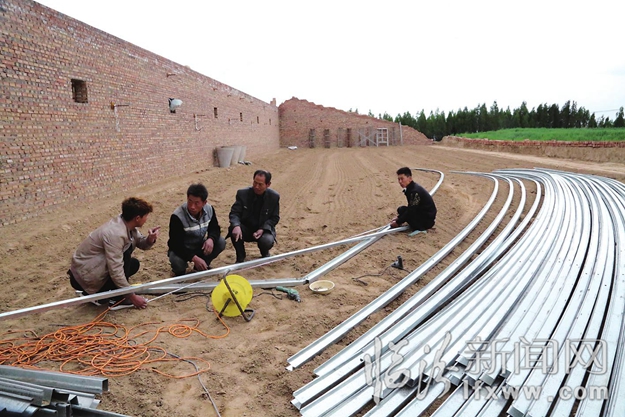 李章云正同河南郑州来的技术人员讨论温室的建设情况。