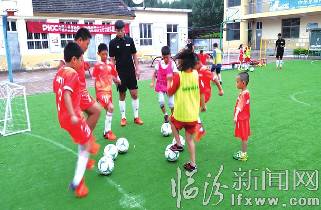 孩子们在绿茵场上苦练足球技巧。